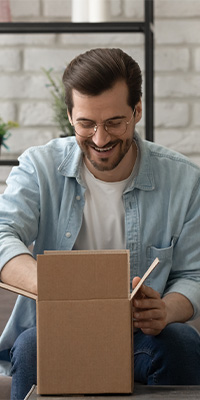 Mentality Shopperprofielen – Nieuwsgierige shoppers, man met bril die lachend een doos opent.