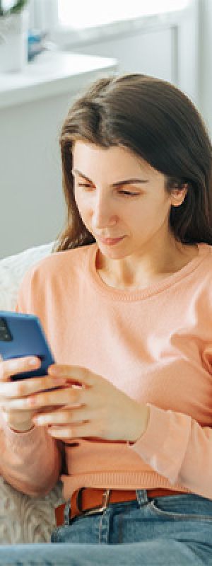 Mentality Mediaprofielen – Kritische verdiepingszoekers, jonge vrouw met kort haar die geconcentreerd op haar telefoon kijkt.