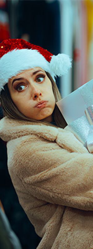 Mentality Financeprofielen – Lichtvaardig impulsieven: jonge vrouw met kerstmuts tijdens winkelen.