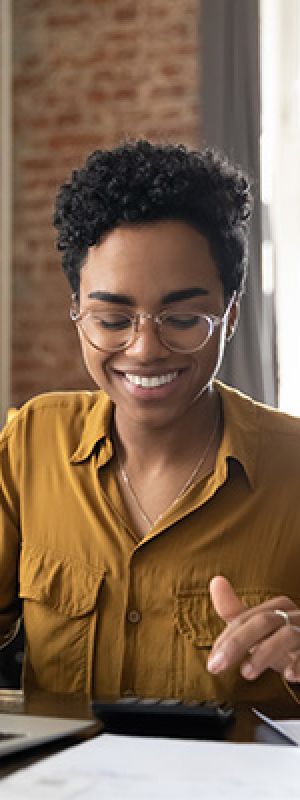 Mentality Financeprofielen – Gecontroleerde genieters: vrouw met bril achter laptop.