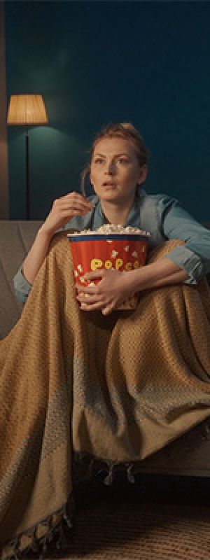 Mentality Mediaprofielen – Statusbewuste thrillseekers, man onder een deken die tv kijkt met een bak popcorn.